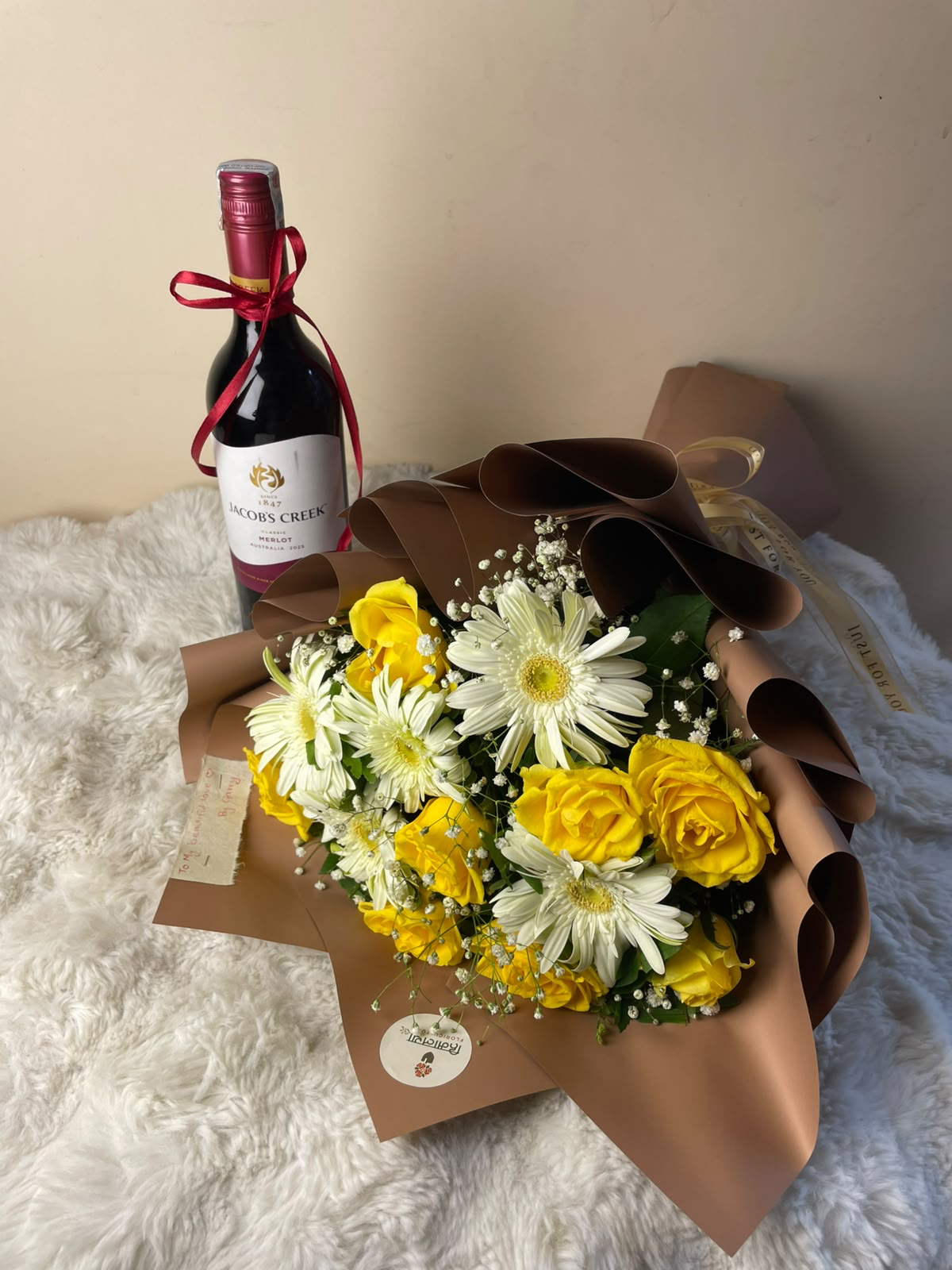 A cheerful gift combination featuring a bottle of Jacob’s Creek, bright yellow roses, and colorful gerberas, complemented by delicate Gypsophila. The premium brown wrapping adds a warm and elegant finishing touch.