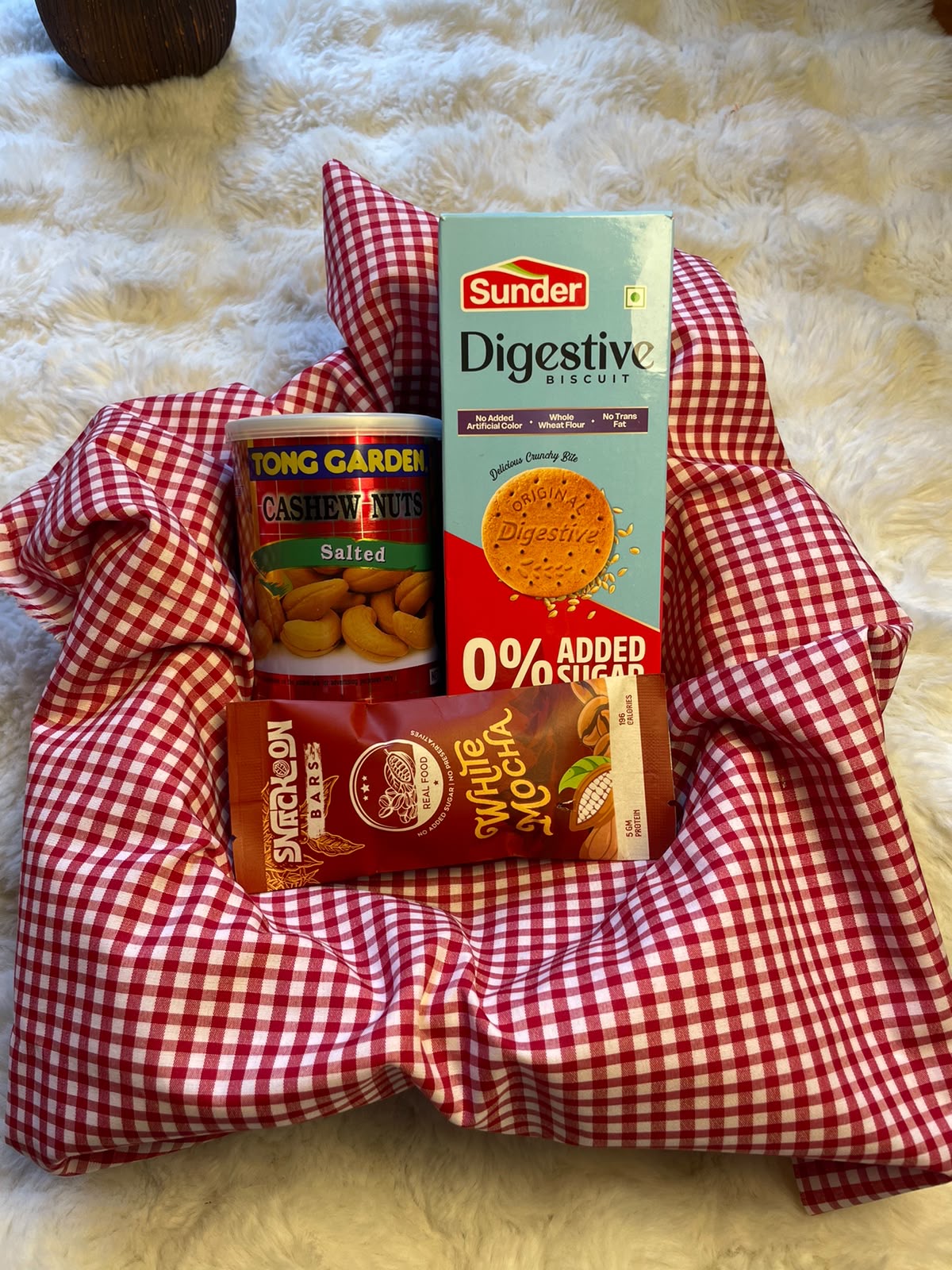 A simple and practical festive gift featuring digestive biscuits, an energy bar chocolate snack, and cashew nuts.