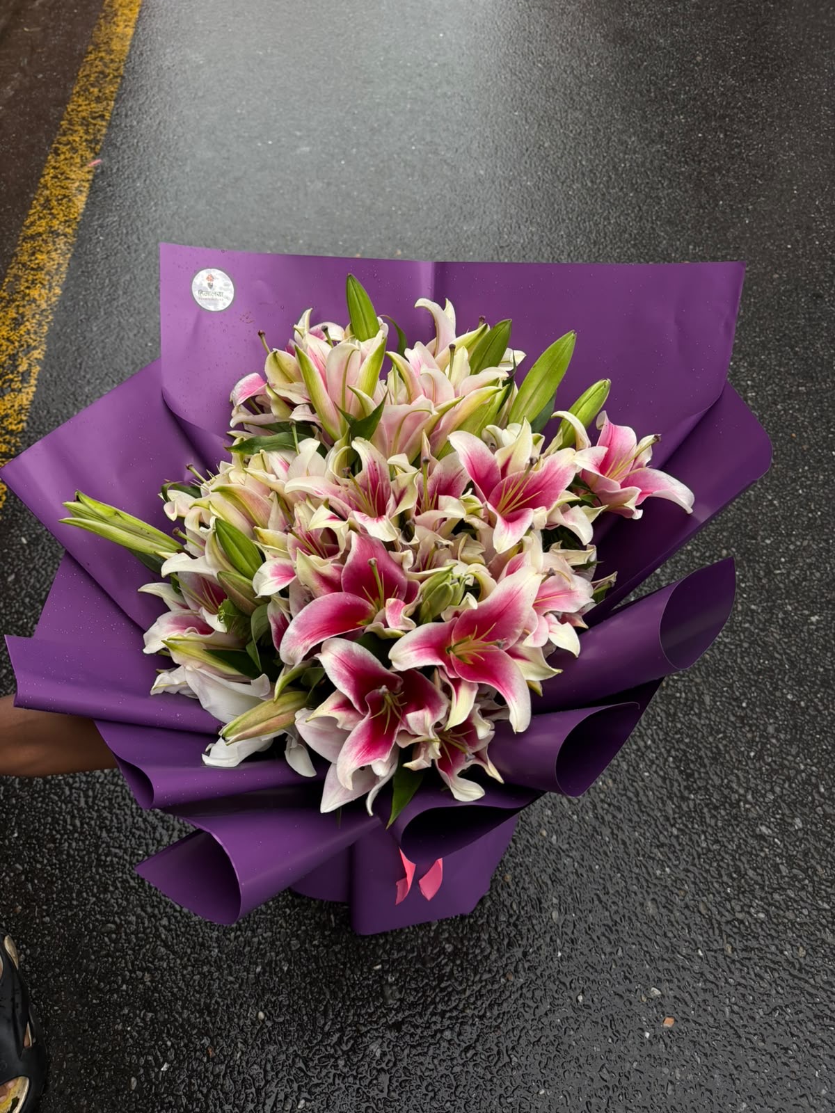 Purple Lily Bouquet An elegant premium arrangement featuring 20 stems of beautiful lilies, carefully arranged and presented in a sophisticated purple wrapper. The graceful blooms and rich presentation create a luxurious look suitable for special celebrations and memorable occasions.