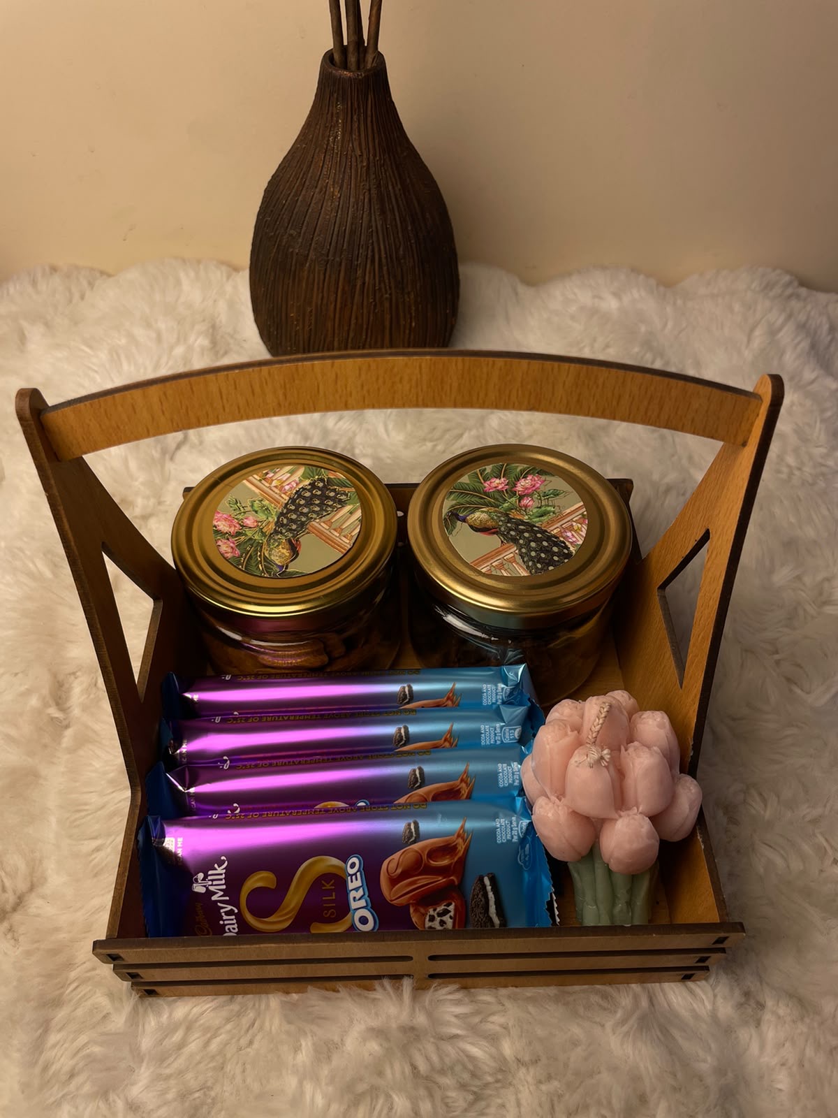 A premium festive hamper featuring two jars of assorted dry fruits and nuts, four Dairy Milk Silk chocolates, and a floral-scented candle.