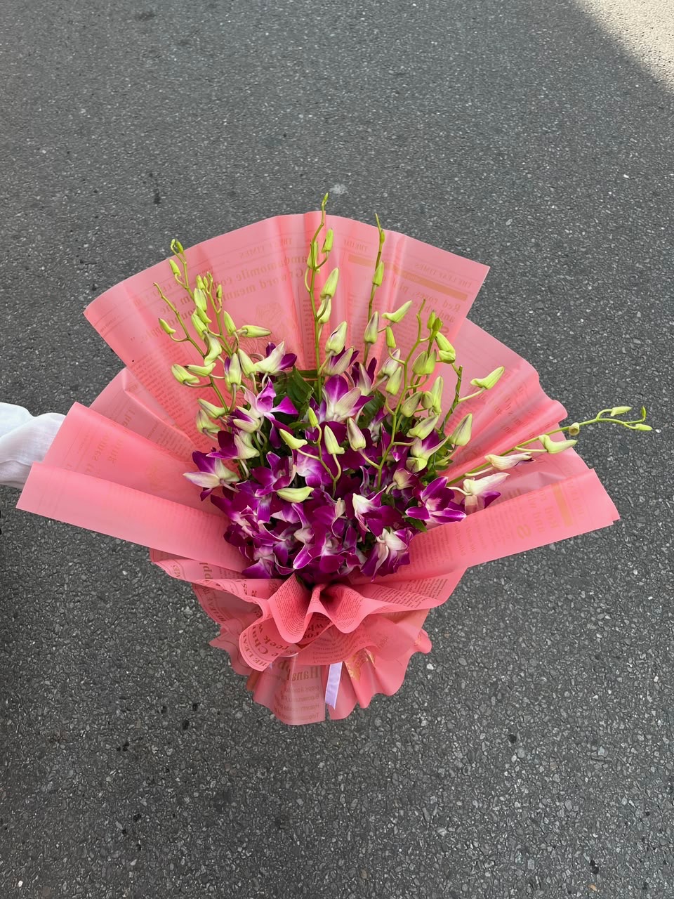 A graceful arrangement featuring 15 stems of fresh orchids, beautifully presented in an elegant pink wrapper. The delicate blooms and soft pink presentation create a sophisticated and luxurious look, perfect for special celebrations and thoughtful gifting.