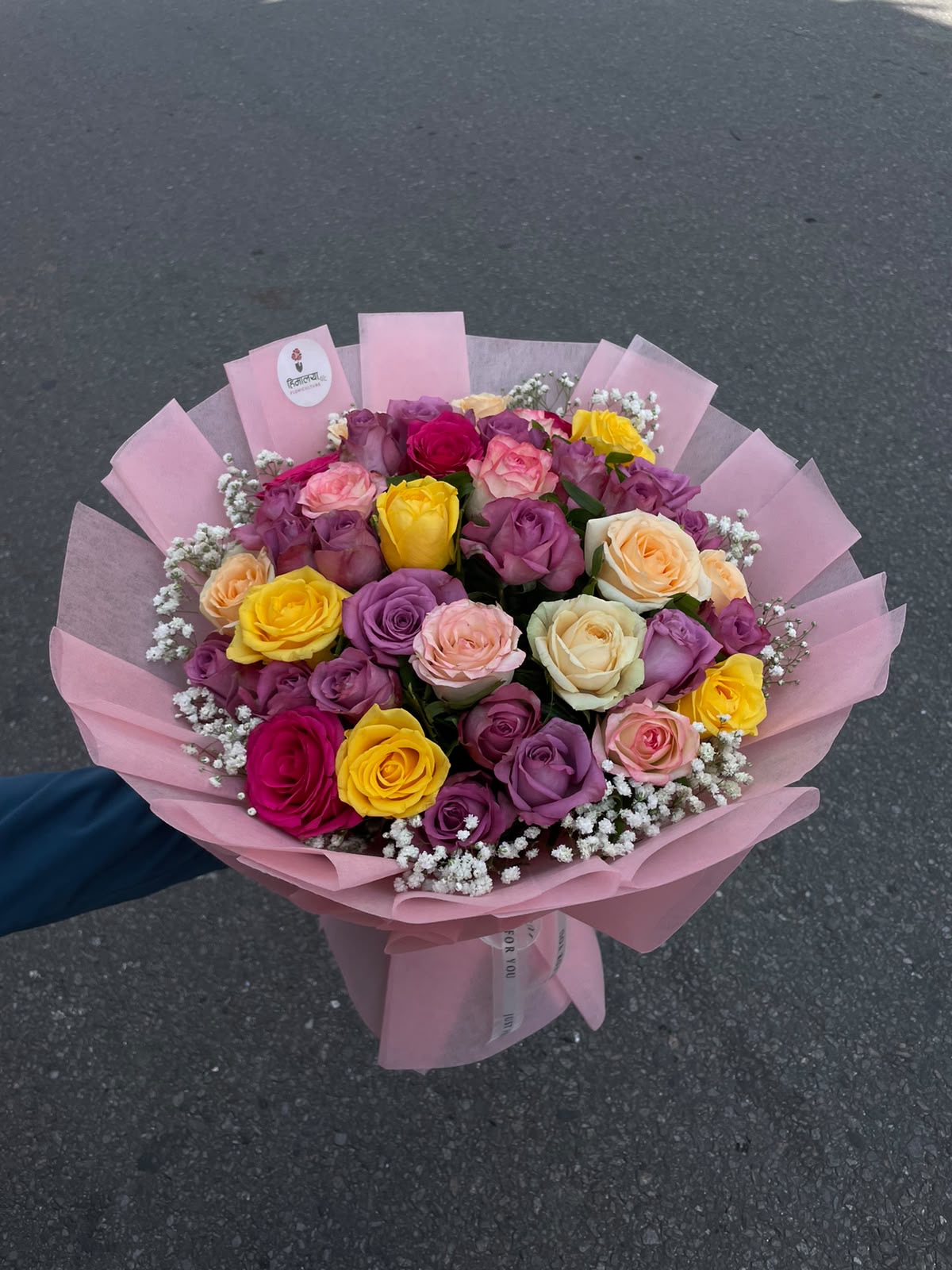 Colorful Rose Delight A vibrant bouquet featuring 40 mixed roses in purple, yellow, peach, and hot pink shades, complemented by delicate gypsophila. Finished with pink wrapping, this bouquet creates a colorful and elegant floral presentation.