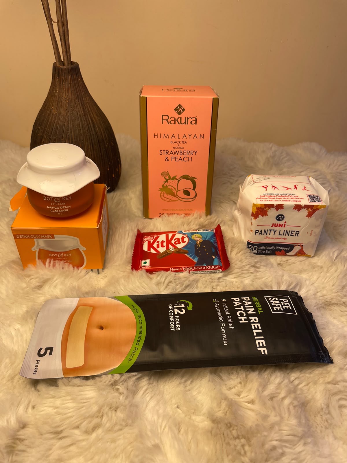Tea & Self-Care Hamper A cozy self-care combination featuring a clay mask, pain relief patch, KitKat, panty liner, and flavored black tea.