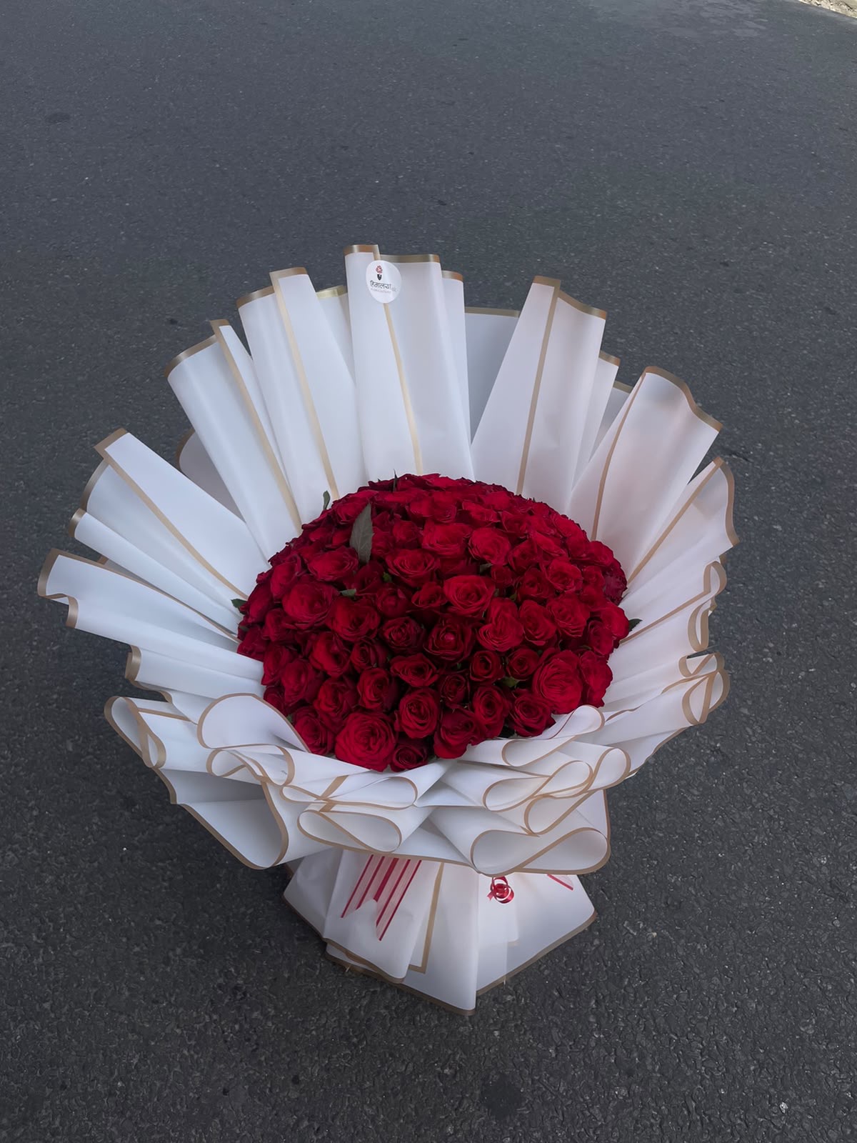 A breathtaking arrangement of 100 vibrant red roses, wrapped in classic white and tied with a bold red ribbon.Designed to create a memorable impression on any special occasion.