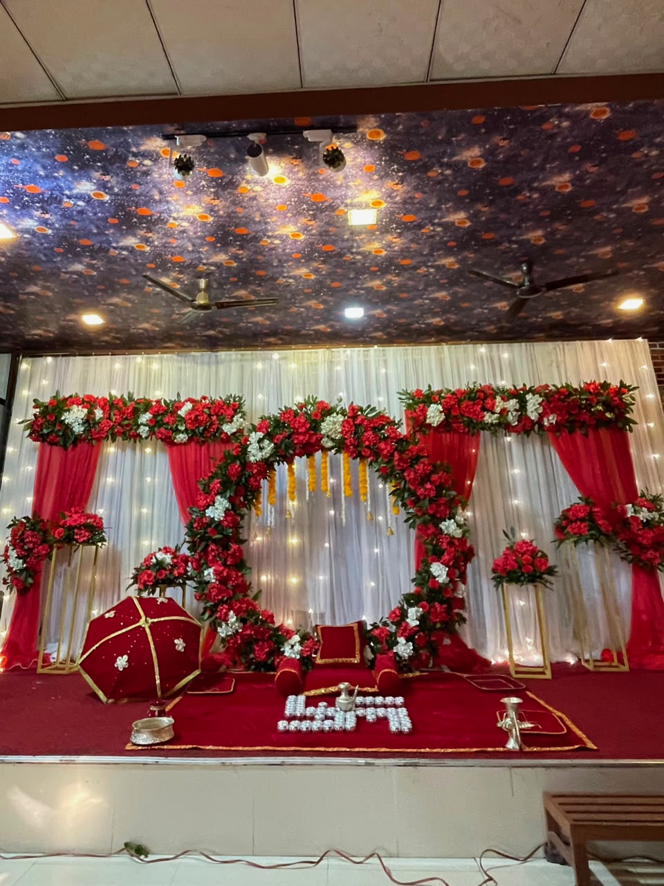 Celebrate your little one's Pasni ceremony with a grand circular stage featuring an elegant white and red artificial flower theme. The beautifully designed circular backdrop, carefully arranged floral accents, and coordinated stage decoration create a luxurious setting for this special cultural milestone. The combination of white and red adds timeless elegance while creating a beautiful focal point for family photographs and ceremonial moments.