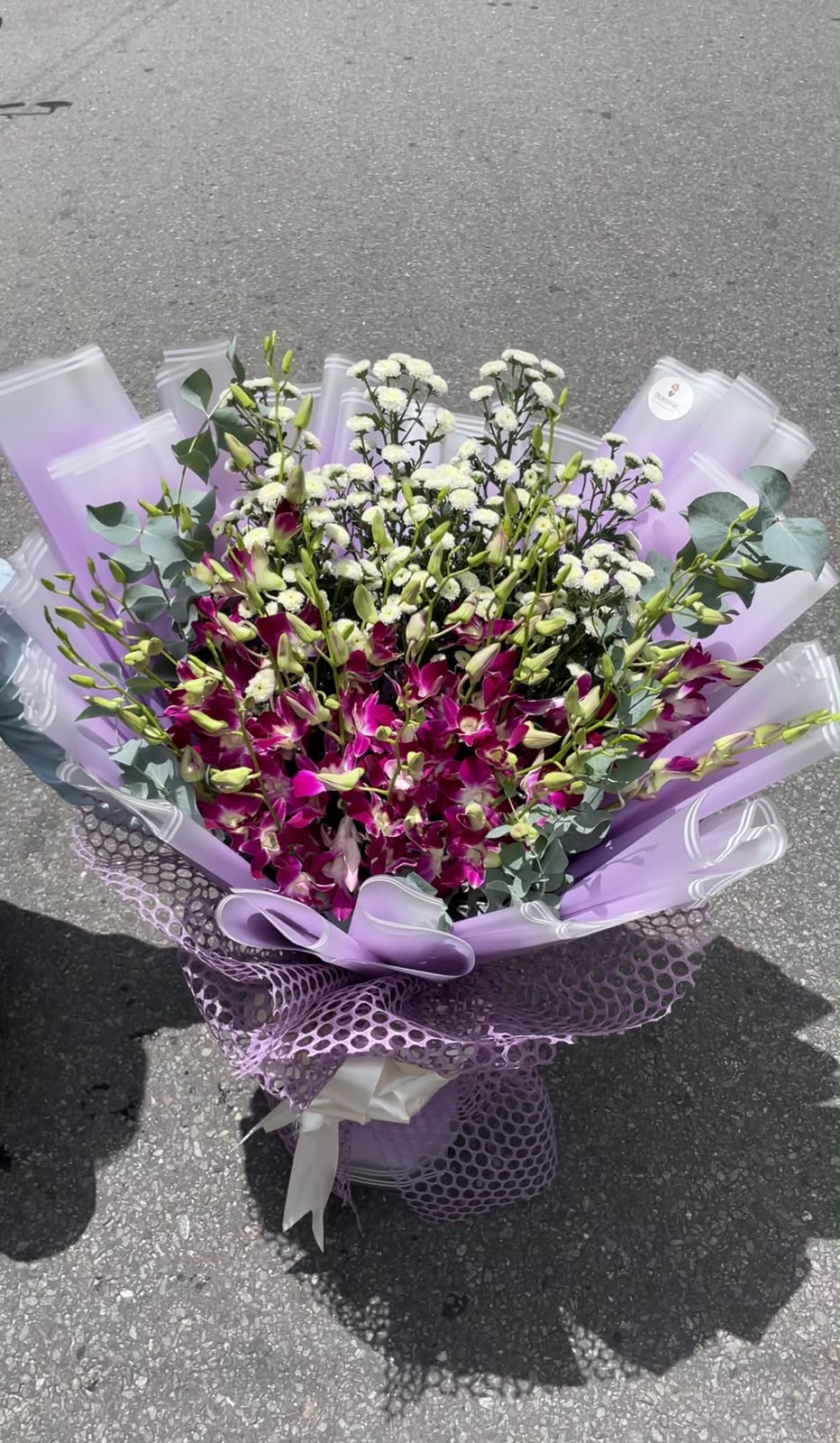 Daisies may be replaced with a suitable premium flower of similar style and value depending on seasonal availability. Orchid variety, bloom size, flower shades, filler flowers, and wrapping may vary slightly while maintaining the bouquet's overall style, quality, and value.