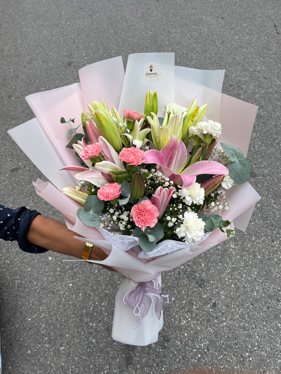 Lilies may be delivered in bud form for maximum freshness. Bloom size, flower shades, filler flowers, and wrapping may vary slightly depending on seasonal availability while maintaining the bouquet's overall style, quality, and value.