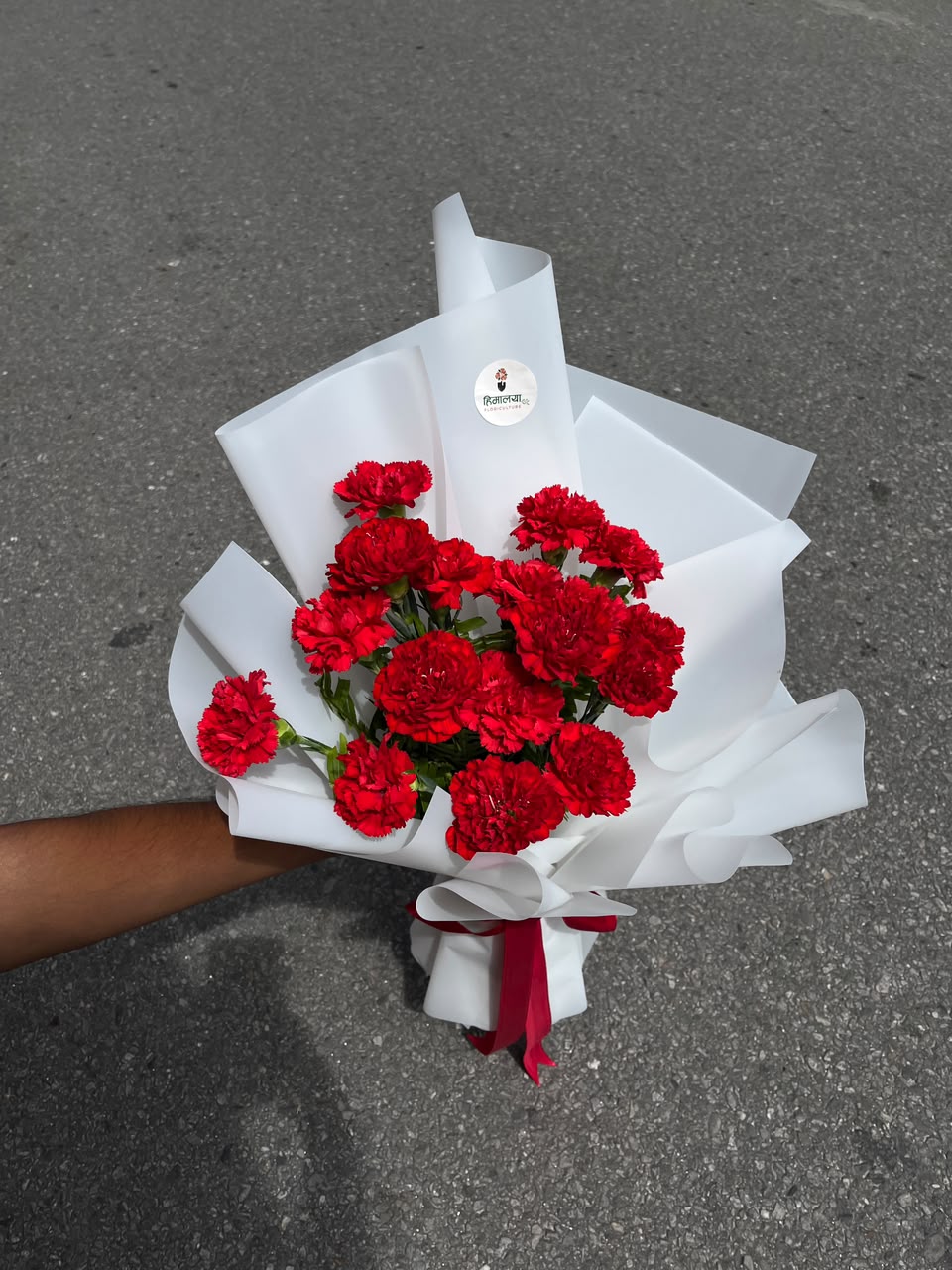 15 Red Carnation Bouquet Flower shades and wrapping may vary slightly depending on seasonal availability while maintaining the bouquet's overall style, quality, and value.