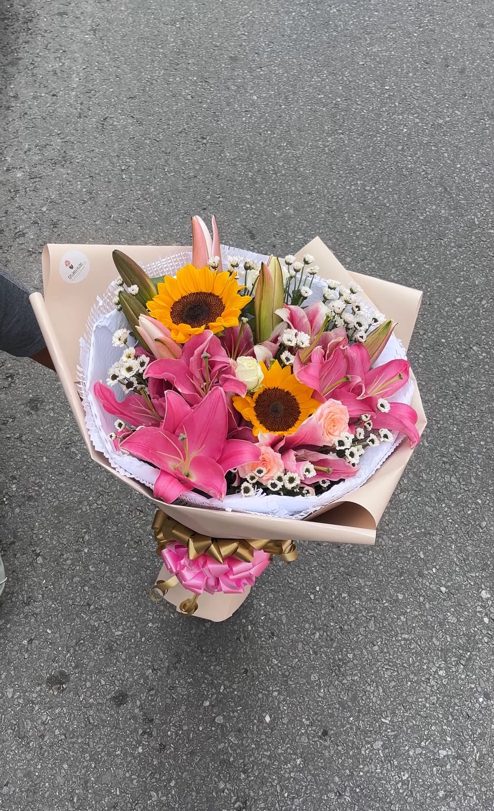 Lily Sun Glow Flowers, wrapping materials, ribbons, and decorative elements may also vary based on availability.