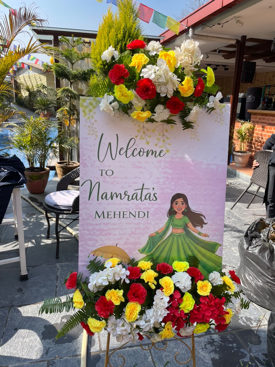 This welcome setup brings warmth, energy, and elegance to any event entrance. The bold yellow and orange floral palette creates an upbeat, celebratory ambiance that immediately catches the eye of arriving guests, serving as both a helpful directional greeting and a beautiful photo backdrop to set the mood for your event.