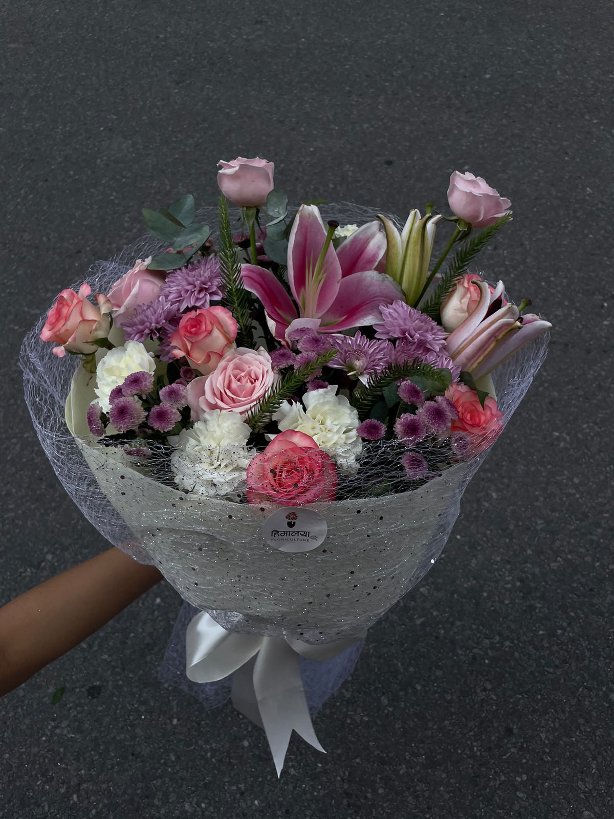 Choose this bouquet for its beautiful combination of soft pastel shades, elegant flowers, and lush greenery. The mix of lilies, roses, carnations, and daisies creates a full and luxurious arrangement that feels both thoughtful and sophisticated. It is a versatile gifting option suitable for a variety of occasions and is designed to make your special moments even more memorable.