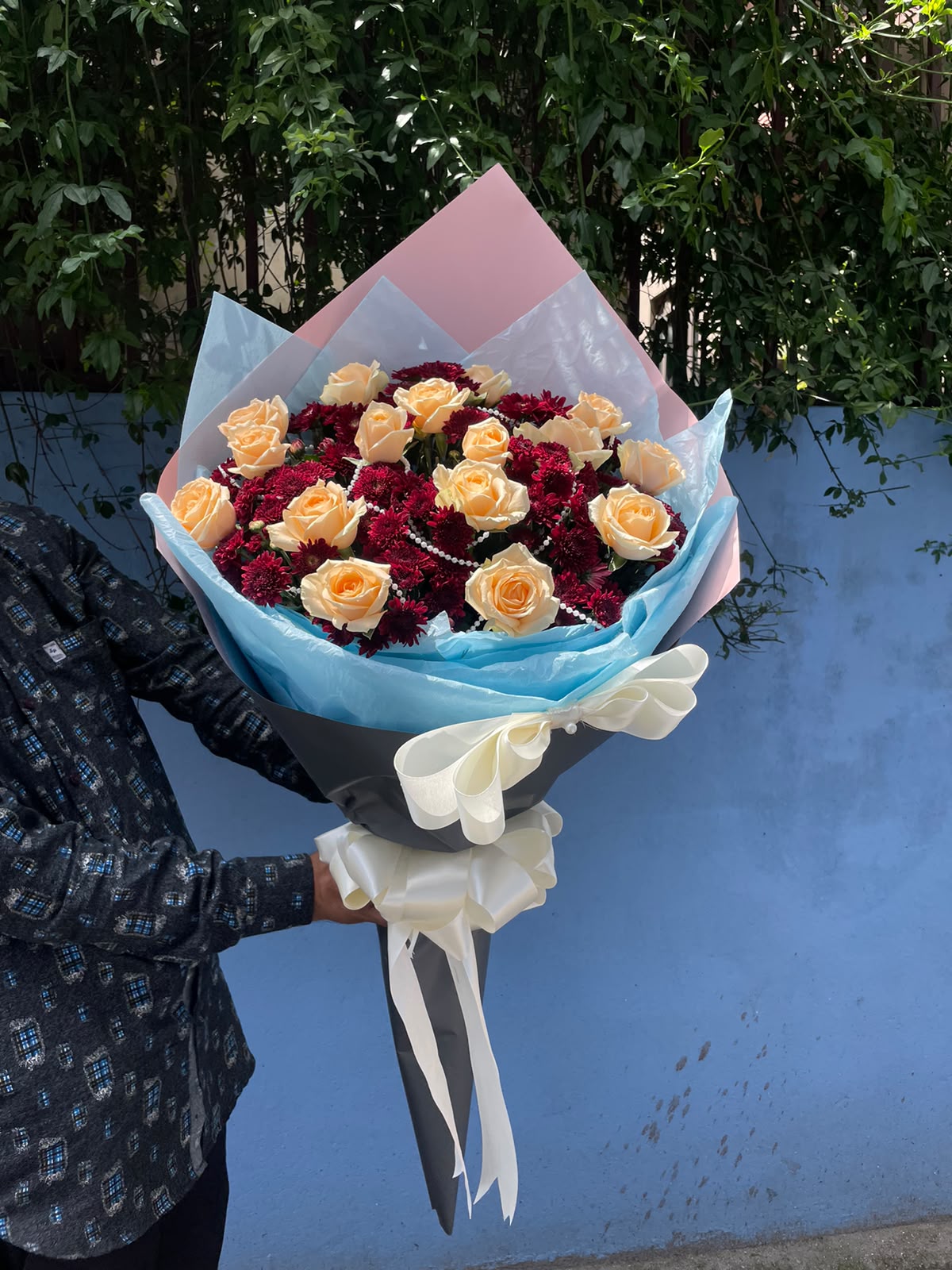 Peach Pearl 25 Red daisies may be replaced with red roses based on availability and season. Flower shades, wrapping, and decorative details may vary slightly.